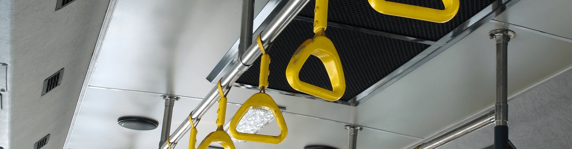 Interior view of a bus featuring yellow grab handles and ventilation system, ensuring passenger comfort and safety.
