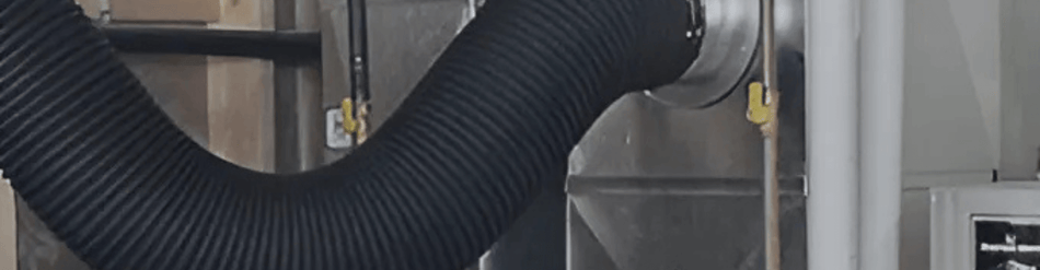 Close-up of a durable black furnace duct cleaning hose attached to an HVAC system for efficient debris extraction.