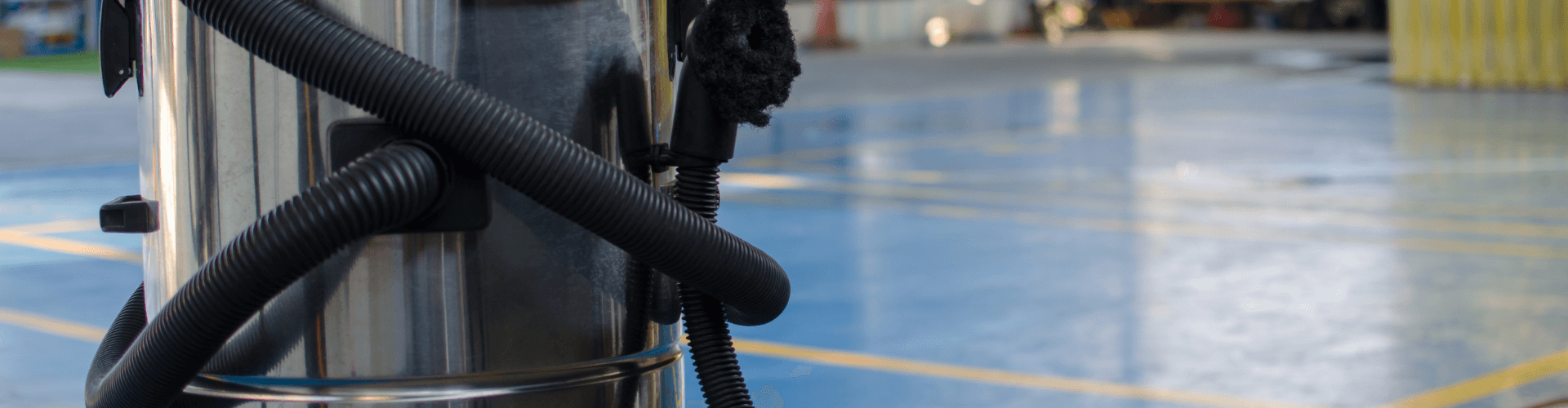 Close-up of a stainless steel vacuum with hoses in a car wash setting, highlighting its functionality.