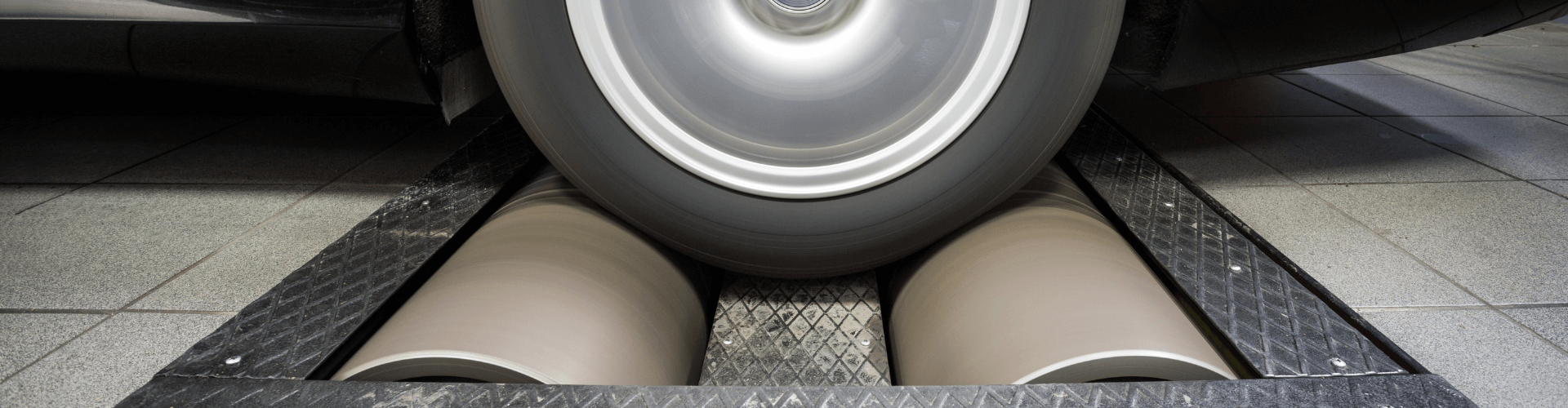 Close-up of a car wheel on dynamometer rollers, illustrating high-performance automotive testing and diagnostics.