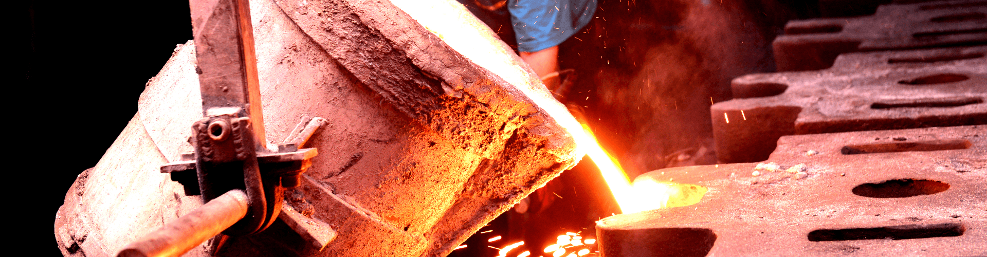 Worker pouring molten metal in a foundry, showcasing hoses designed for extreme heat and abrasive conditions.