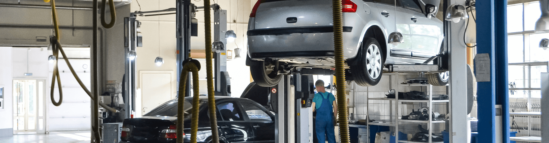 Garage exhaust system effectively removing vehicle fumes in a busy auto service center with cars being serviced.