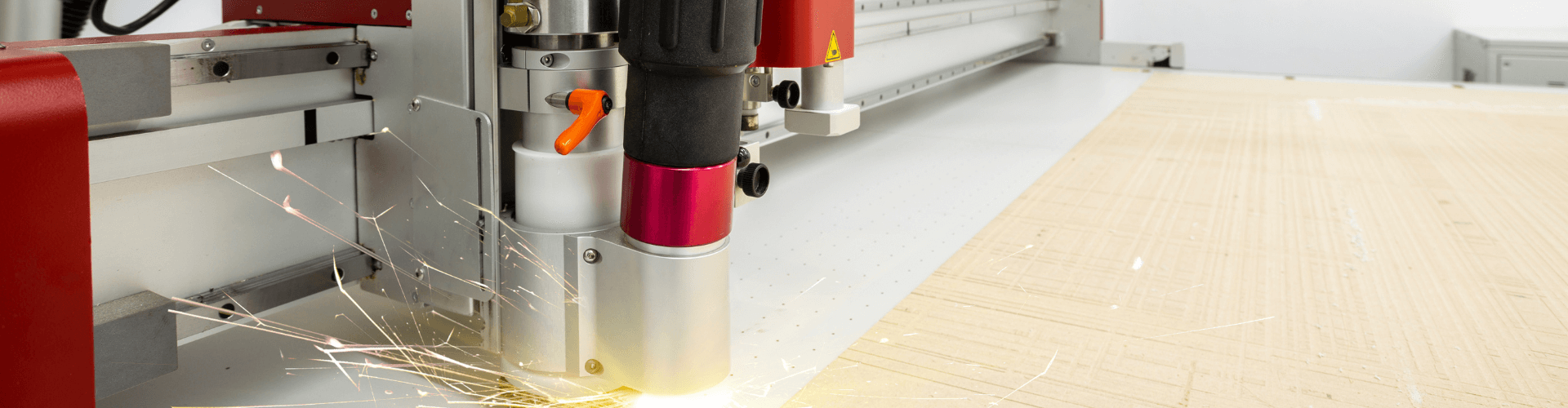 Laser engraving machine in action, producing sparks while working on wood material.