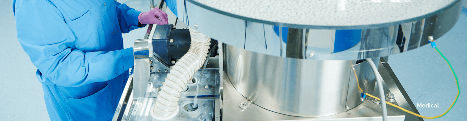 Healthcare professional working with medical-grade equipment and ventilation hoses in a cleanroom environment.