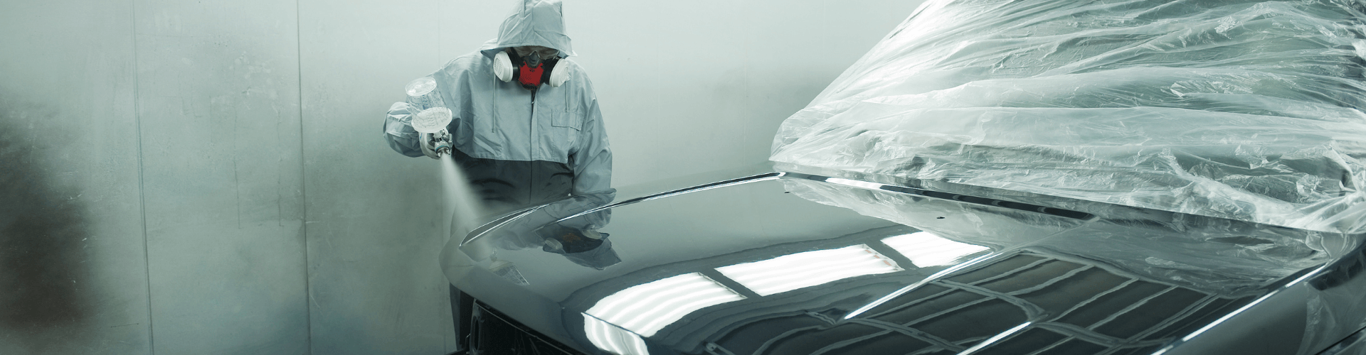 Spray painting a car in a booth, demonstrating paint spray extraction in a chemical-resistant environment.