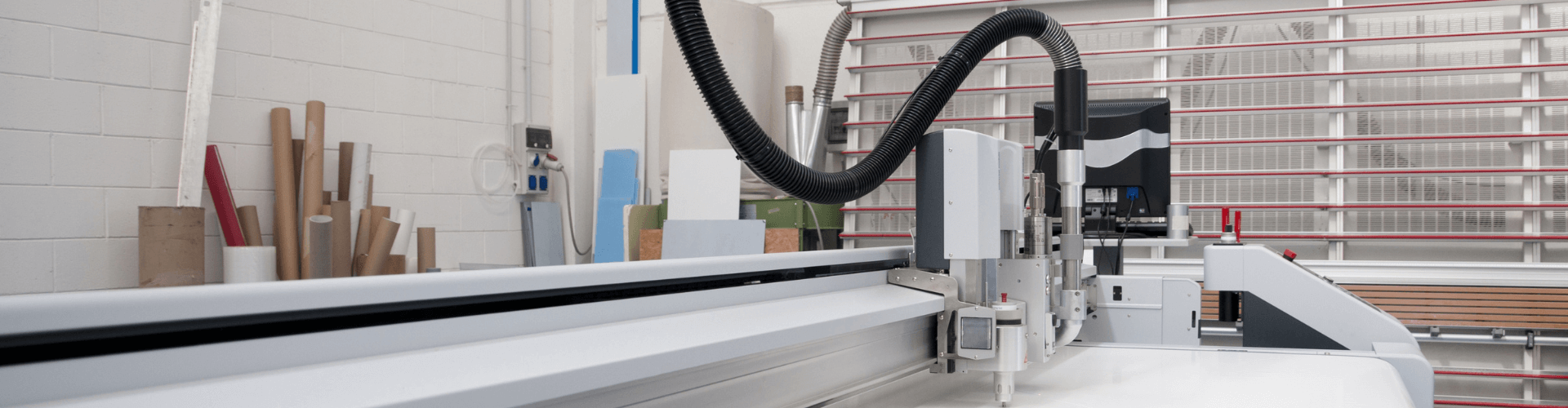 Image of a precision cutting machine equipped with a flexible black suction hose for efficient paper trim removal.