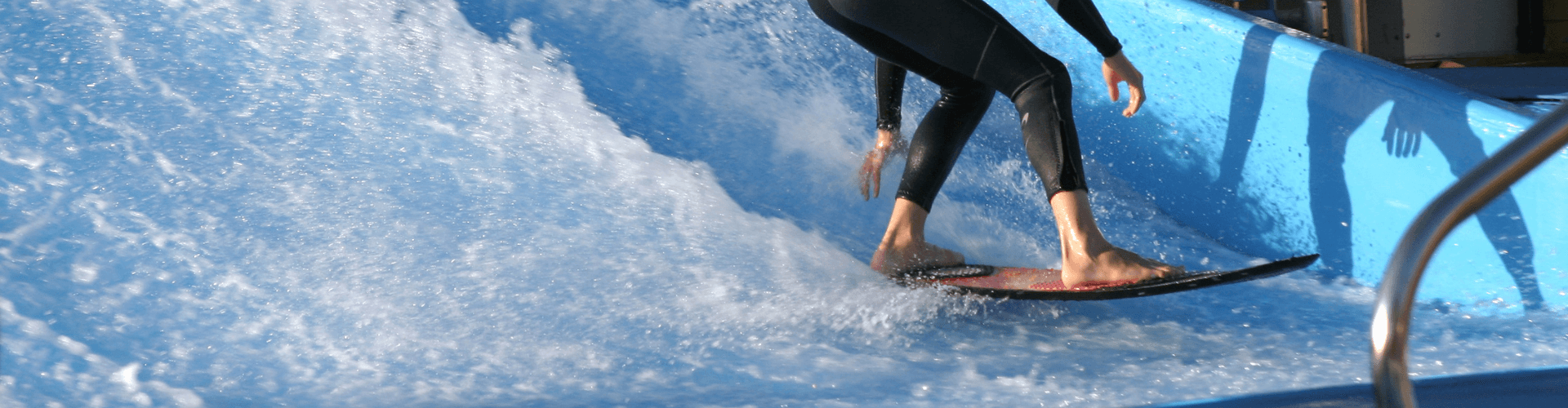 Surfer riding a wave in a wave pool, showcasing the dynamic motion and fun of simulated surfing.