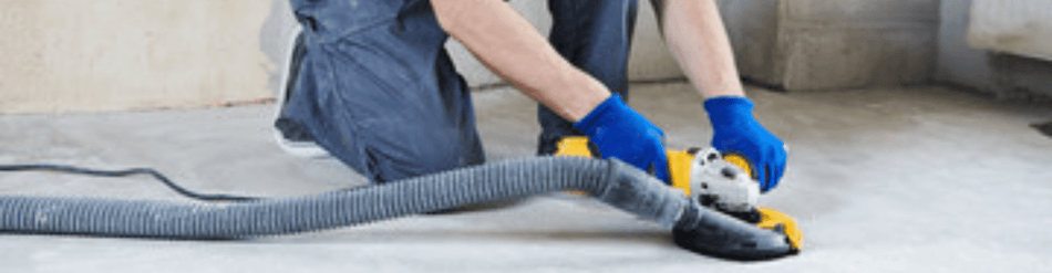 Worker using a grinder with a dust extraction system to eliminate airborne dust in a construction area.