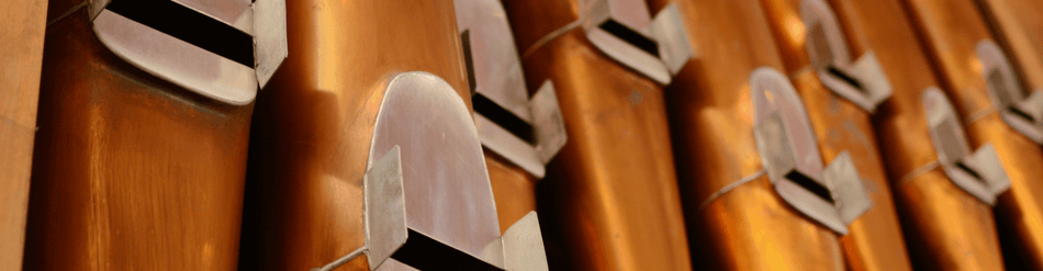 Close-up of copper pipes in a pipe organ showcasing airflow direction for optimal tonal quality.