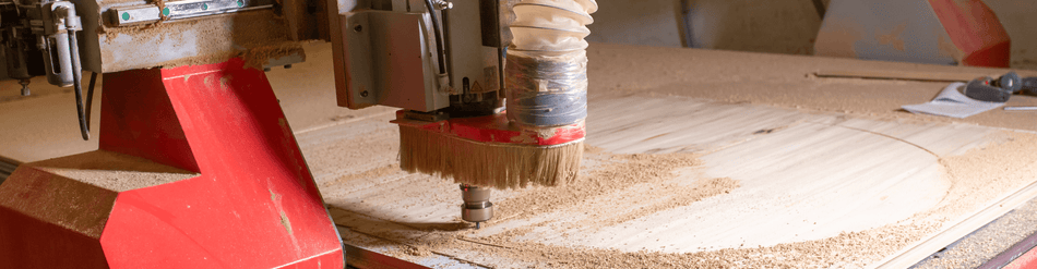 CNC machine in operation with dust extraction, showing precision wood manufacturing and chip removal.