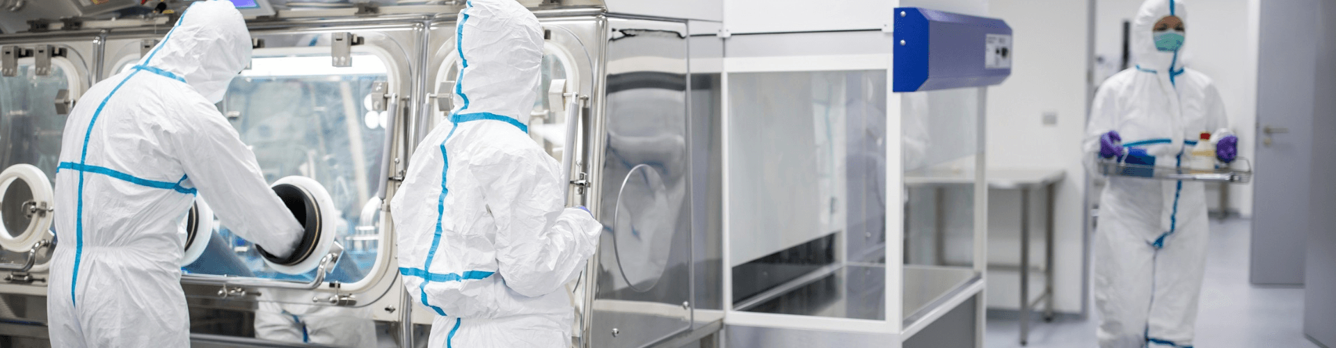 Workers in cleanroom suits operate sterile equipment in a cleanroom environment, ensuring low particulate levels.
