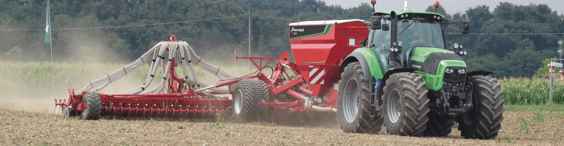 Fertilizer broadcasting tractor with a red spreader applying granular fertilizers in an agricultural field.