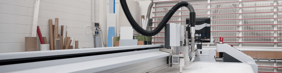 Image of a precision cutting machine equipped with a flexible black suction hose for efficient paper trim removal.