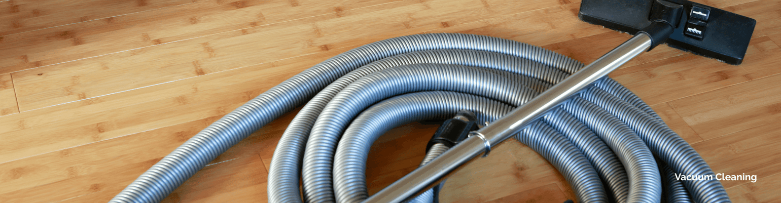 Close-up of vacuum hose and attachment on wooden floor, showcasing commercial cleaning equipment features.