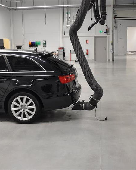 Black car with a vacuum hose attached in a warehouse setting