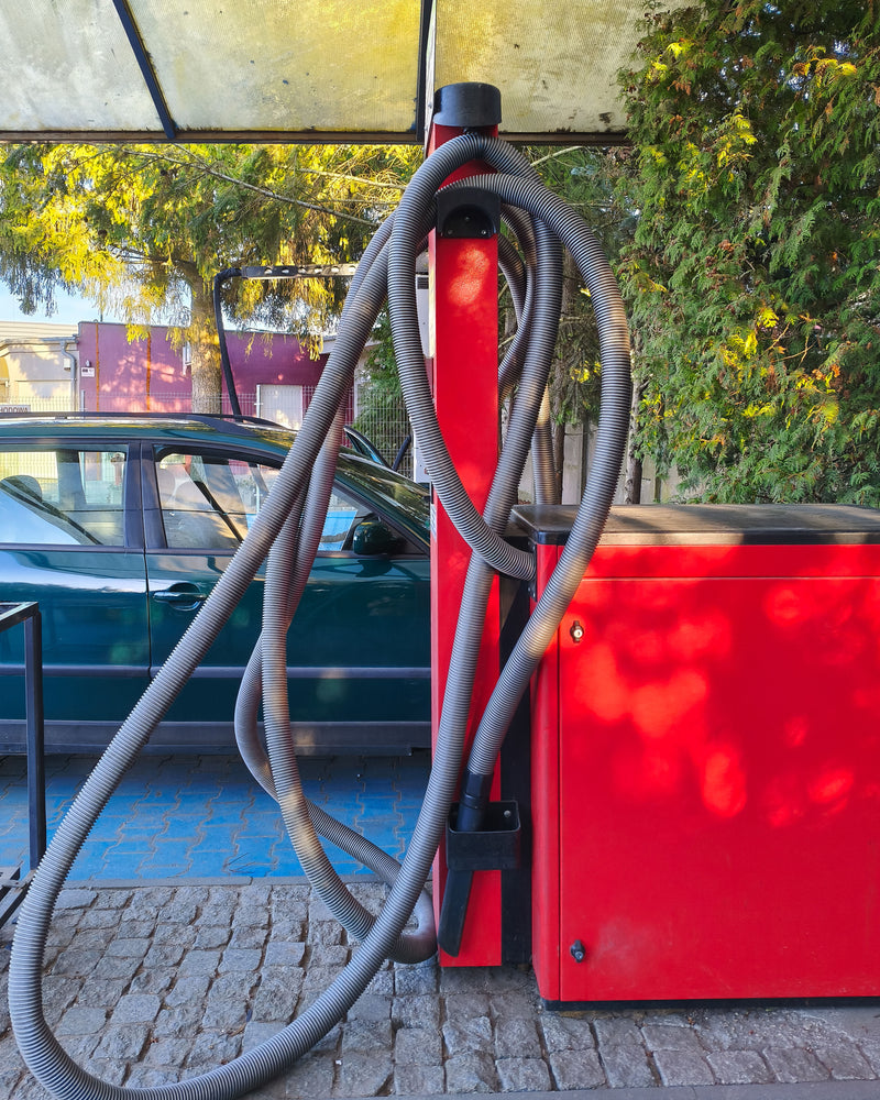 Red vacuum with grey hose at a car wash car port