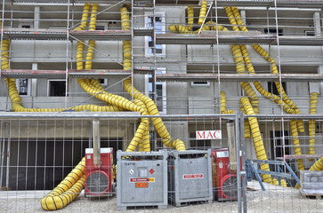 Yellow ventilation hoses and equipment in front of a building.