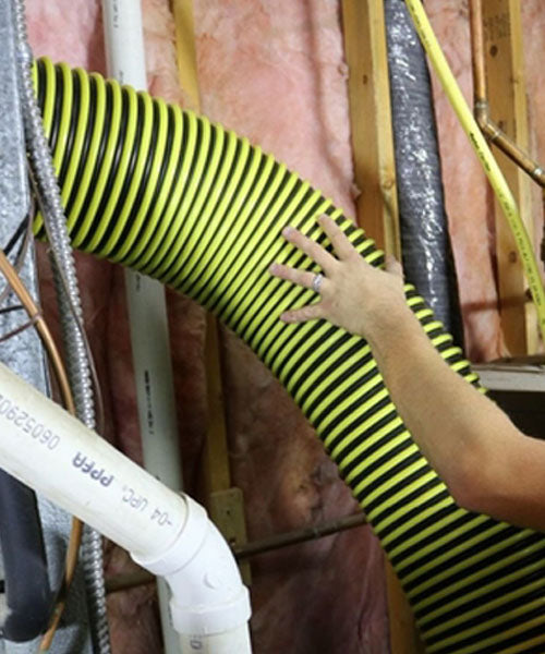Person adjusting a yellow and black striped duct in an indoor setting