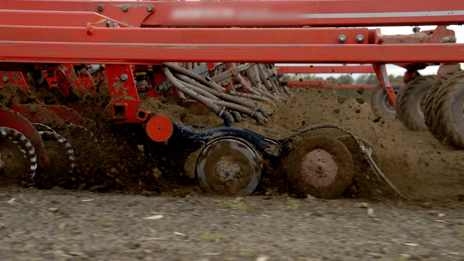 Red agricultural seeder in action on a field