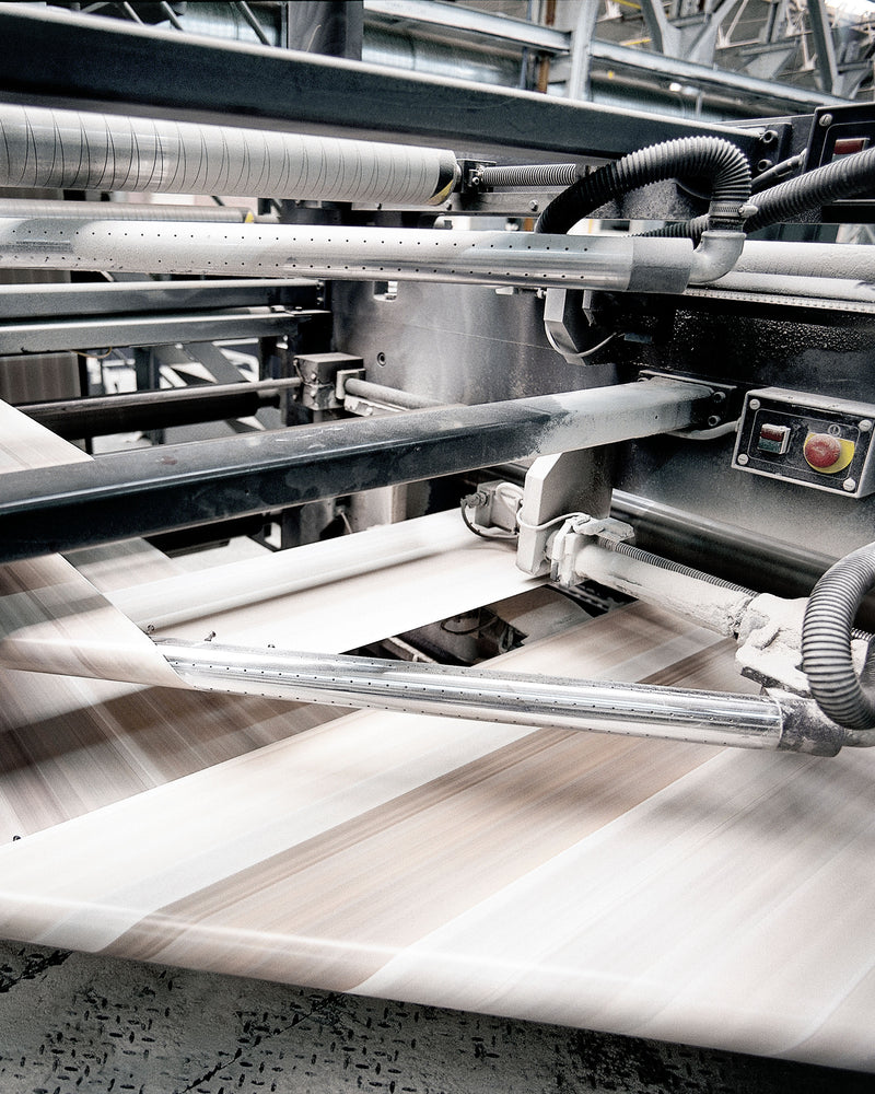 Close-up of a machine with metal components and paper, likely in an industrial setting.